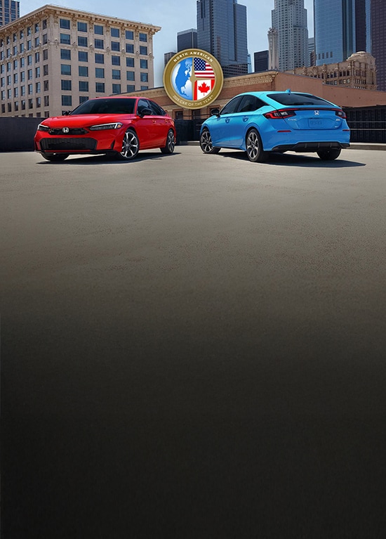 2025 Honda Civic Sedan Sport Touring Hybrid shown in Rallye Red and Civic Hatchback Sport Touring Hybrid shown in Boost Blue Pearl parked on a rooftop, with buildings on the background